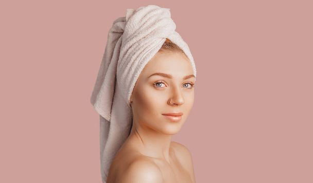 Beautiful sensual young girl with clean skin on a pink background with a mockup. Topless woman in a towel. The concept of spa treatments, natural beauty and care, youth, cream and mask, freshness - 写真・画像