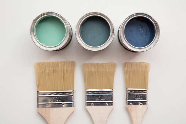 Overhead view of a DIY paint brush with green and blue sample paint pots - Fotoğraf, Görsel