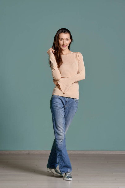 Full length portrait of trendy young woman in beige jersey longsleeve and straight blue jeans - Foto, Imagem