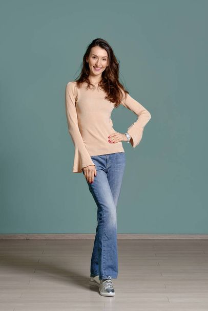 Full length portrait of trendy young woman in beige jersey longsleeve and straight blue jeans - Foto, Imagem