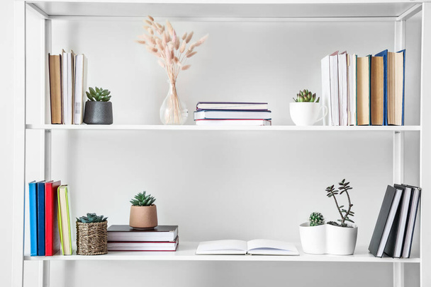 Shelf unit with books and decor near light wall - Foto, immagini