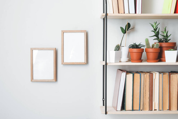 Shelf with books and plants hanging on light wall - Photo, Image