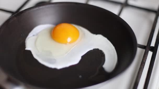 Chiuda di uova fritte in padella per friggere nera. Concetto colazione. - Filmati, video