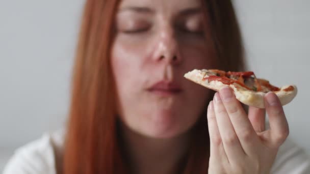 Close-up portret van een blanke vrouw met een lekker Italiaans stuk pizza klaar om te eten. Hongerige vrouw, sluit af. Blanke vrouw houdt plak pizza - Video