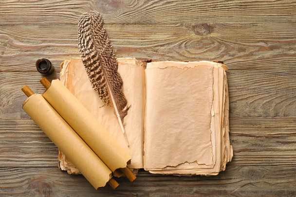 Открыть старую книгу со свитками, чернилами и перьями на деревянном фоне - Фото, изображение