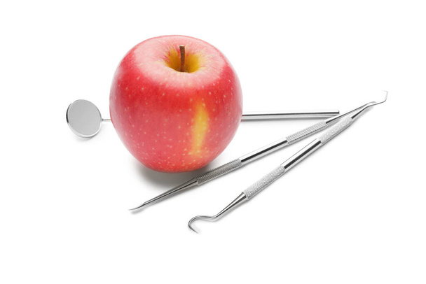 Εργαλεία οδοντίατρου με μήλο σε λευκό φόντο - Φωτογραφία, εικόνα