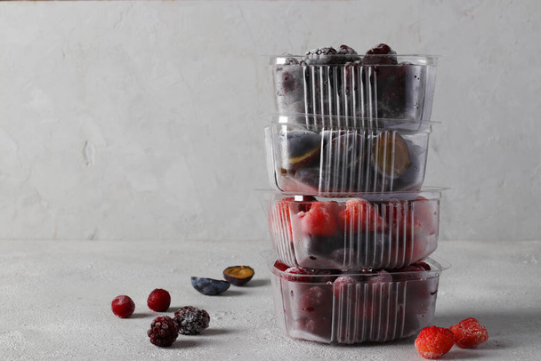 Bagas congeladas, como cerejas, morangos, ameixas e amoras nas caixas de armazenamento no fundo cinza concreto. Espaço para texto - Foto, Imagem