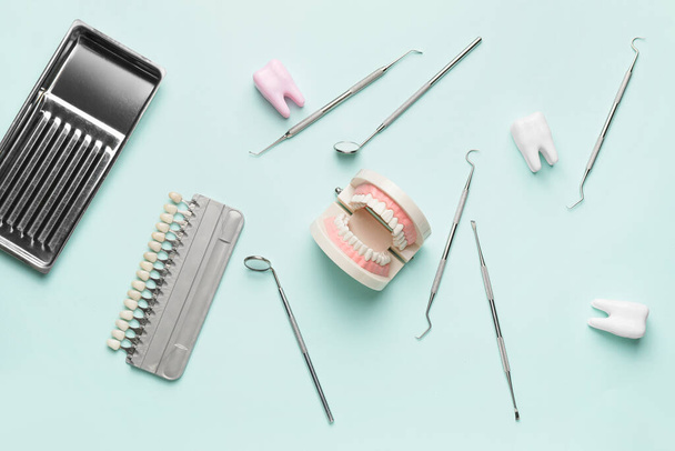 Инструменты стоматолога, модель челюсти и образцы зубов на цветном фоне - Фото, изображение