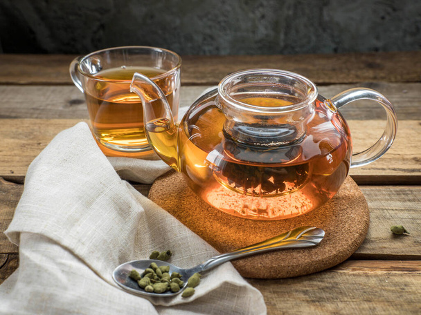 Ginseng-Tee in einer Teekanne. Ginseng Oolong Teeaufguss in einem Teelöffel, einer Teekanne und einer Tasse Ginseng Oolong Tee auf einem Holztisch.   - Foto, Bild