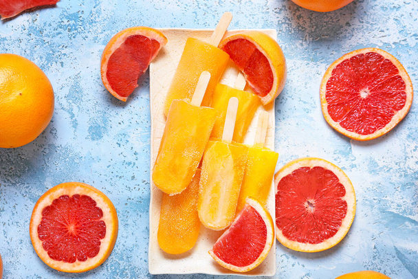 Plate with tasty ice-cream and grapefruits on color background - Photo, Image
