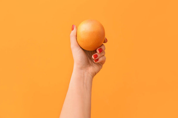 Woman holding ripe grapefruit on color background - Foto, afbeelding