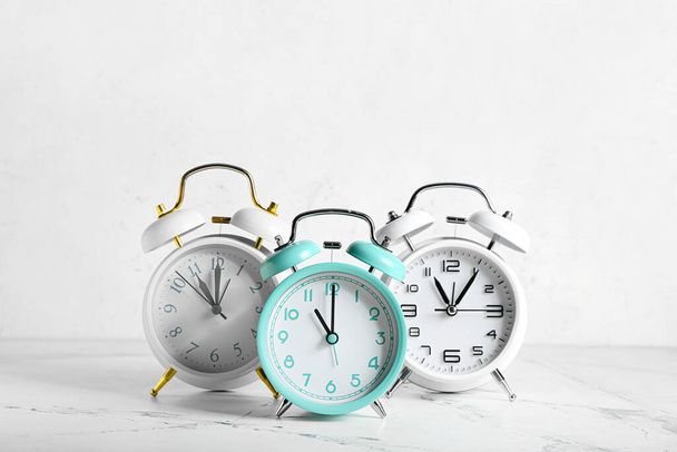 Different alarm clocks on light background - Foto, Imagen