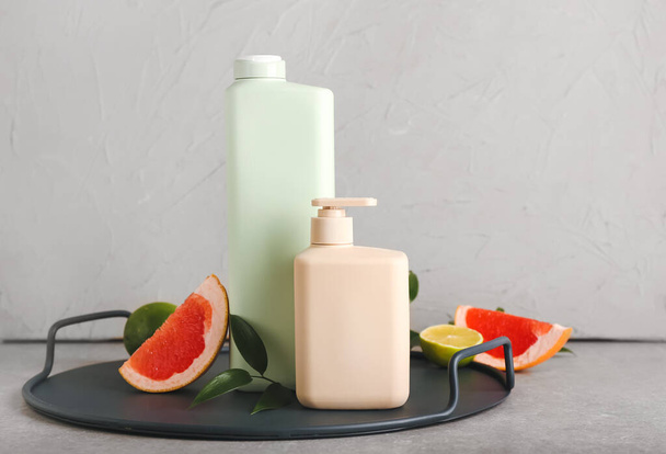 Flaschen Duschgel und Früchte auf grauem Hintergrund - Foto, Bild