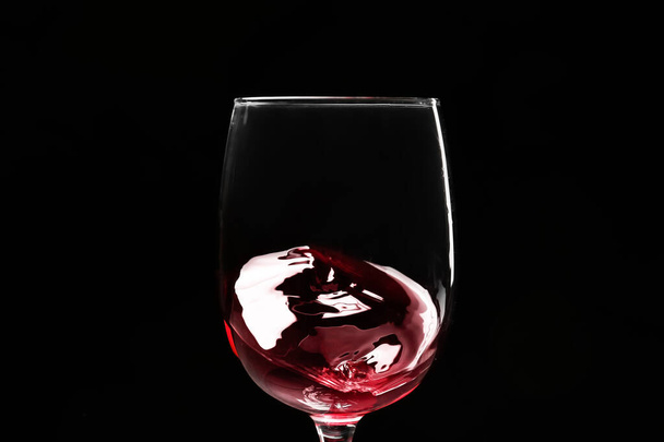 Bicchiere di vino con spruzzata su sfondo scuro, primo piano - Foto, immagini