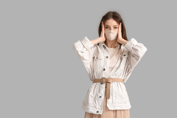 Fashionable young woman wearing mask on grey background - Foto, Imagen