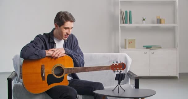 Beyaz tenli yetenekli genç müzisyen gitar çalmak için cep telefonu kullanıyor. Akıllı telefon kamerasına konuşuyor. Vlog çevrimiçi blog yayınları internet üzerinden ev konseri veriyor. - Video, Çekim