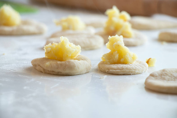 el proceso de hacer pasteles con patatas en casa en la cocina sobre una mesa blanca, hábitos caseros con patatas - Foto, imagen