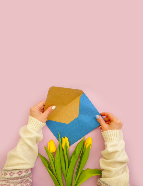  женские руки держат конверт, букет тюльпанов - Фото, изображение