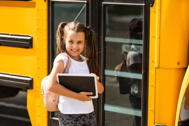 Dziewczyna z plecakiem w pobliżu żółtego autobusu szkolnego. Transport dla studentów - Zdjęcie, obraz