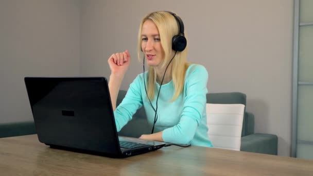 kobieta freelancer ze słuchawkami rozmawia w wideo czacie za pomocą laptopa. - Materiał filmowy, wideo