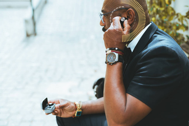A profile portrait of an elegant mature bald African-American man inserting a wireless headphone into his ear to listen to music, a radial graph element around his ear as a concept of volume adjusting - Foto, Imagem