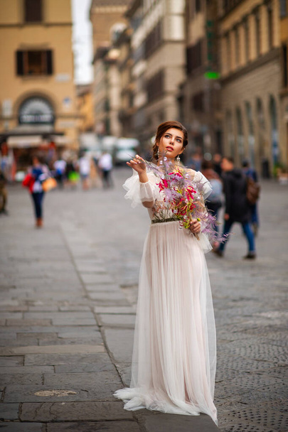 a bride in a wedding dress with a Venetian mask in her hands in Florence.Italy. - Fotografie, Obrázek