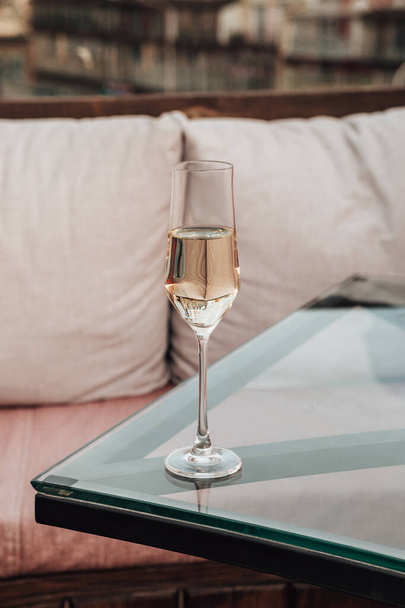 Vertikale Nahaufnahme eines Kristallglases mit gekühltem Champagner, das auf dem Esstisch im Restaurant steht, Blasen im Inneren. Alkoholgetränk mit Kopierraum und Bokeh-Hintergrund. - Foto, Bild
