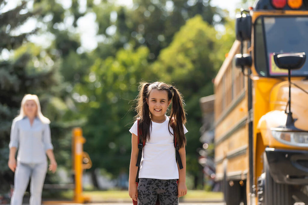 Мать привозит дочь в школу возле школьного автобуса. назад в школу - Фото, изображение