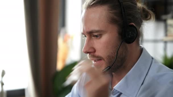 Close-up of handsome bearded friendly caucasian guy, operator of call center, support service, business leader, conducts distant consultation uses headset, talks with customer by online call  - Footage, Video