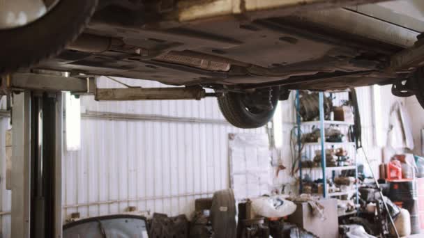 サービスステーションのリフト上の自動車整備士の修理車 - 映像、動画