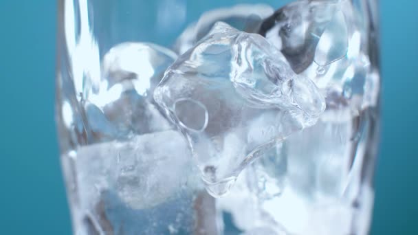 Soda ya da kırmızı sıvıyla doldurulmuş bir bardaktaki buz küplerini yakın plan çek. Kromakey için mavi ekran arka planında kokteyl - Video, Çekim