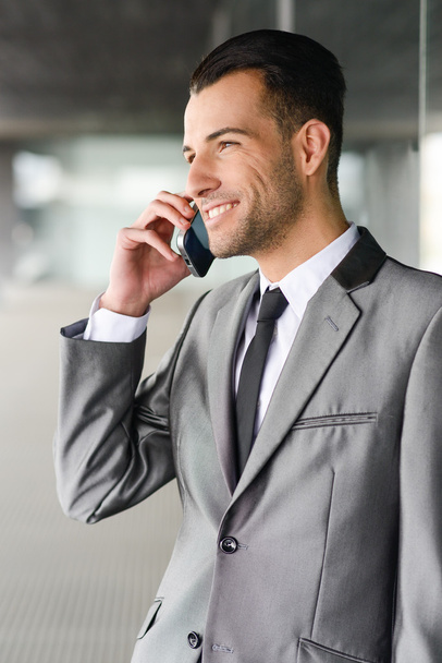 Atractivo joven empresario al teléfono en un edificio de oficinas
 - Foto, Imagen