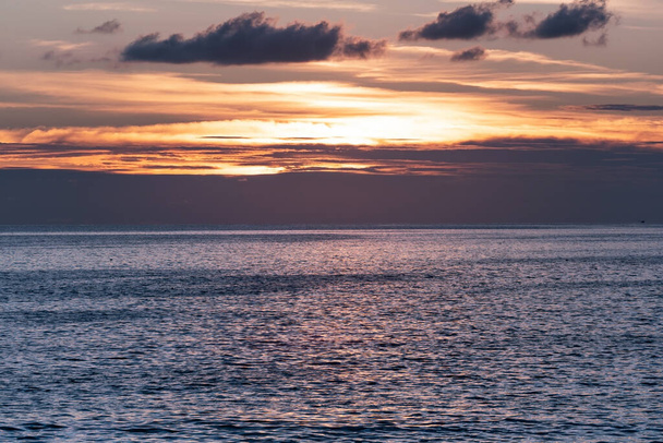 Καταπληκτικά πολύχρωμα σύννεφα στο χρόνο ηλιοβασιλέματος Όμορφο φως της φύσης πάνω από τη θάλασσα Καταπληκτικά χρώματα του ήλιου που δύει Μεγαλοπρεπή σύννεφα που ρέουν στο ηλιοβασίλεμα Χρυσός ουρανός ώρα Βραδινά σκοτεινά σύννεφα. - Φωτογραφία, εικόνα
