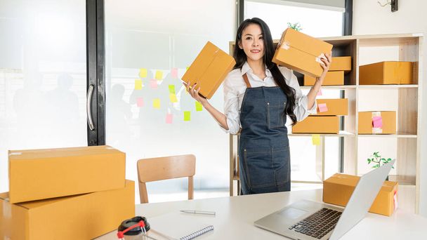 Small business, SME owner, entrepreneurs, young Asian women, check online orders on laptops at home to prepare to pack boxes, sell to sme customers, online business ideas. - Photo, Image