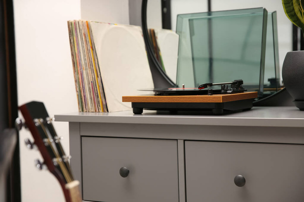 Stylish turntable with vinyl record on chest of drawers indoors - Foto, Imagen