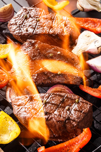 Beef steak on a barbecue grill with flames with vegetables - 写真・画像