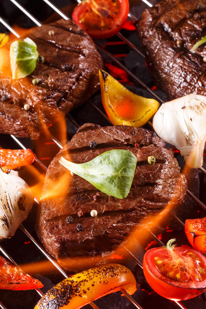 Beef steak on a barbecue grill with flames with vegetables - 写真・画像