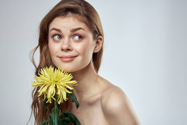 Porträt einer schönen Frau mit einer gelben Blume auf hellem Hintergrund, beschnitten mit Copy Space Model - Foto, Bild