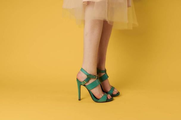Female feet green shoes elegant style fashionable shoes yellow background - 写真・画像