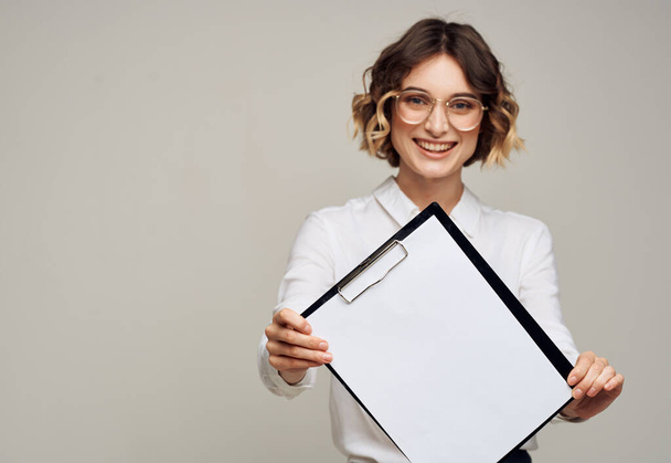 Szczęśliwa kobieta w okularach trzyma teczkę z białą kartką makiety - Zdjęcie, obraz