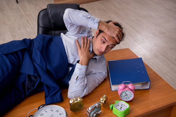 Joven empleado masculino durmiendo en la oficina en la gestión del tiempo co - Foto, Imagen