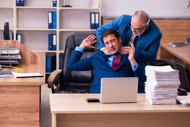 Old male boss and his young male assistant in bullying concept - Photo, Image