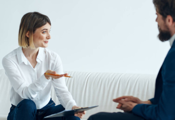 A man in a suit sits on a chair and a woman on a sofa psychologist communicating - Photo, Image
