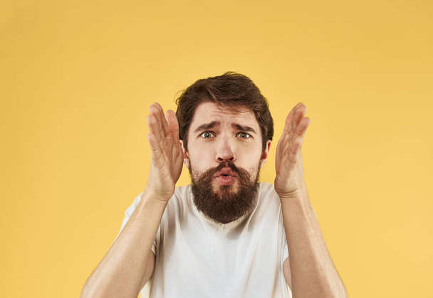Bearded man holding hands near face on yellow background close-up cropped view - Foto, Imagem