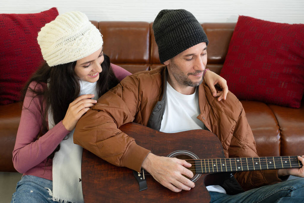 Biały chłopak gra na gitarze z dziewczynami w salonie. koncepcja pary razem - Zdjęcie, obraz