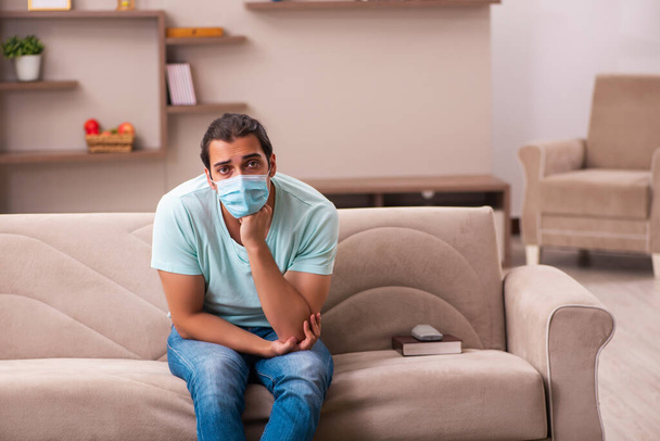 Młody mężczyzna siedzi w domu podczas pandemii - Zdjęcie, obraz