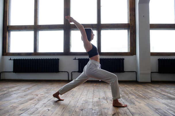 Woman in her living room in warrior yoga pose. - Foto, Bild