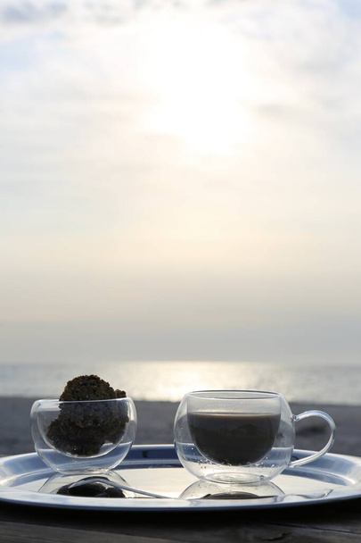 morning coffee on the silver plate  in the sunbeams of dawn on the seashore - Photo, Image
