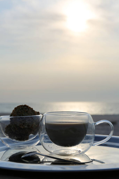 café du matin sur la plaque d'argent dans les rayons du soleil de l'aube sur le bord de la mer - Photo, image