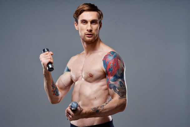 сексуальний спортсмен із зануреними м'язами рук та моделлю здорово-вітамінів гантелі
 - Фото, зображення